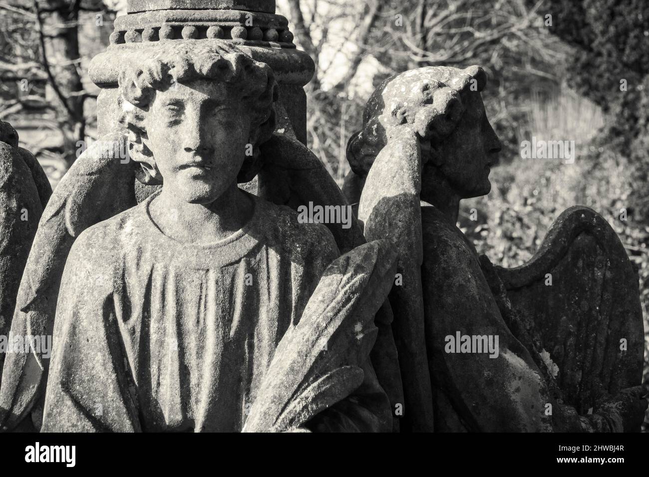 Quatre anges de pierre assis autour d'un monument de cimetière entiné avec des briques Banque D'Images