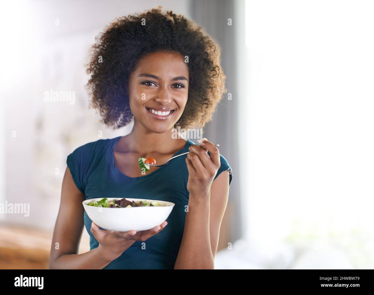 Obtenir ses verts. Portrait d'une jeune femme attrayante mangeant un bol de salade. Banque D'Images