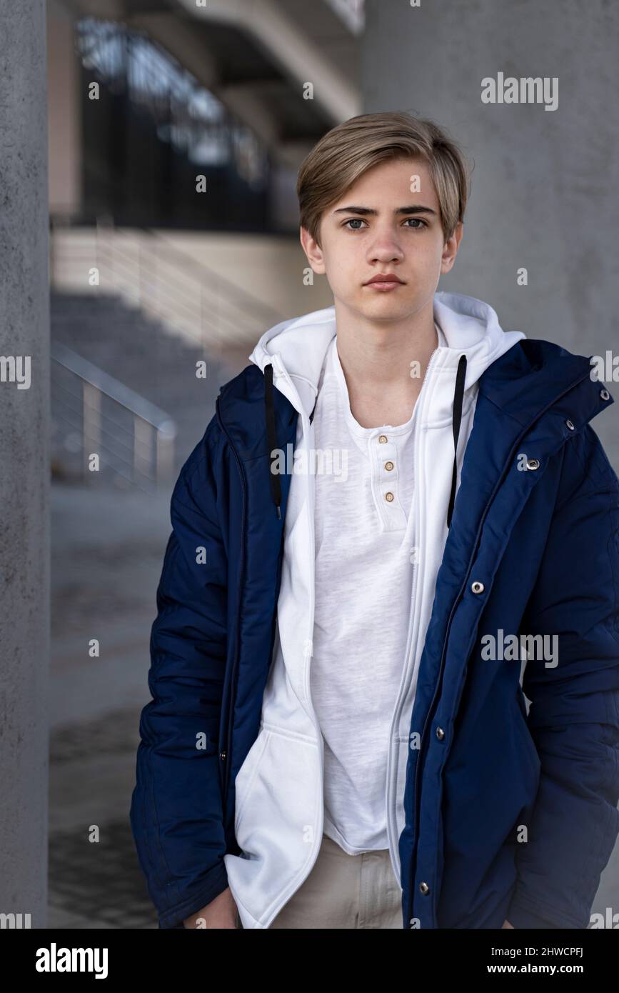 Portrait d'un adolescent. Un adolescent dans une veste bleue et un t-shirt blanc regarde la caméra. Verticale Banque D'Images