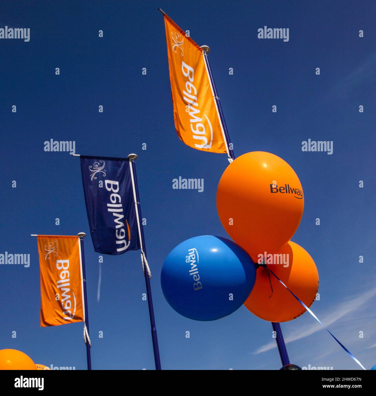 Ballons et drapeaux orange et bleus à l'extérieur d'un développement de maisons Bellway, maisons neuves constructeurs, ciel bleu. Banque D'Images