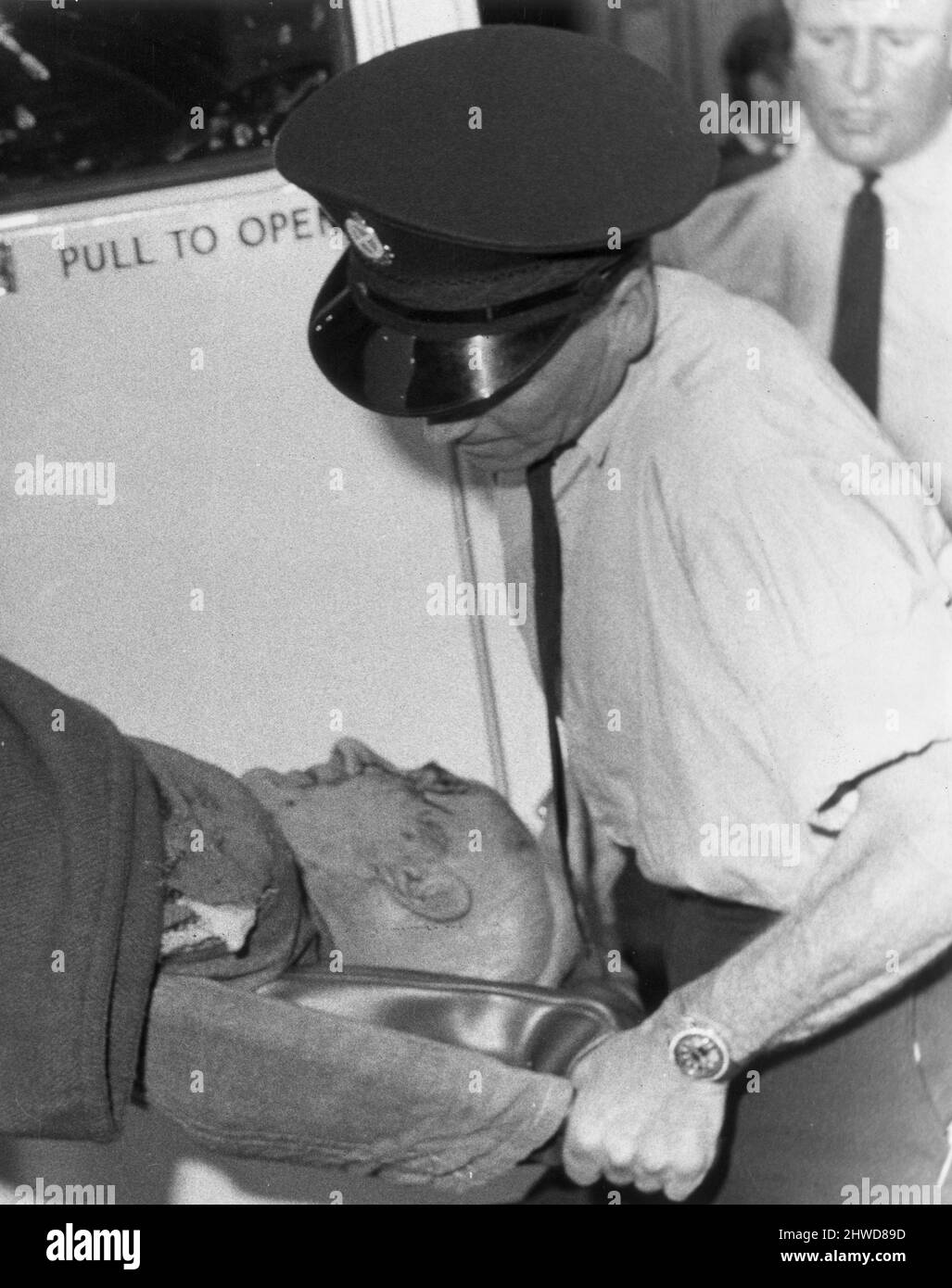 Tirez sur Holyrood Crescent à Woodside, Glasgow, où James Griffiths, âgé de 34 ans, a été assiégé dans son appartement du dernier étage par la police après avoir ouvert le feu avec un fusil et un fusil sur des personnes dans la rue. Le tireur a finalement été abattu par la police après l'avoir encorré dans un bloc d'appartements suite à une poursuite de voiture de 60 km/h. spectacles sur photo : le vendeur James Kerr, son visage couvert de sang, est aidé dans une ambulance. Le tireur l'avait abattu alors qu'il était assis dans sa voiture avant de l'ordonner et de voler la voiture. 16th juillet 1969. Banque D'Images