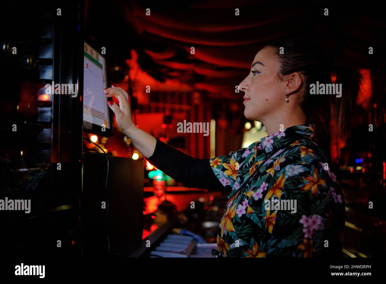 Femme utilisant un ordinateur à écran tactile en travaillant derrière le comptoir dans un bar ou un pub. Banque D'Images