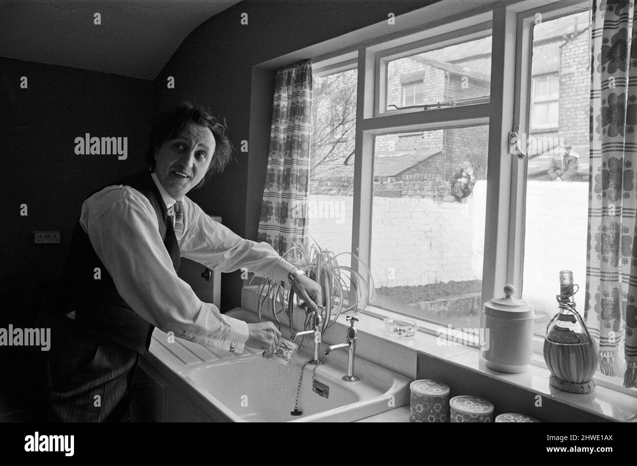 Le comédien Ken Dodd ouvre des appartements à Ducie Street et Beaconsfield Street, Toxteth, Liverpool. Deux maisons, une dans chaque rue, ont été converties en appartements sous la direction d'une équipe d'experts en logement et en planification. Ken boit une tasse d'eau dans la nouvelle cuisine de Mme Mrgaret Gibbs, rue Ducie. 7th avril 1970. Banque D'Images