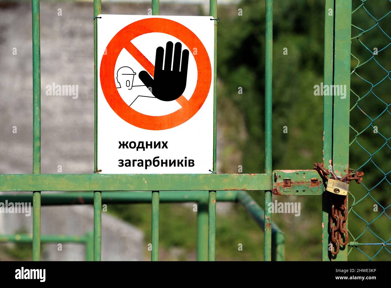 Signe rouge avec une grande main noire indiquant de s'arrêter et grand message 'No Invaders' en ukraine langue sur une porte fermée avec un cadenas Banque D'Images