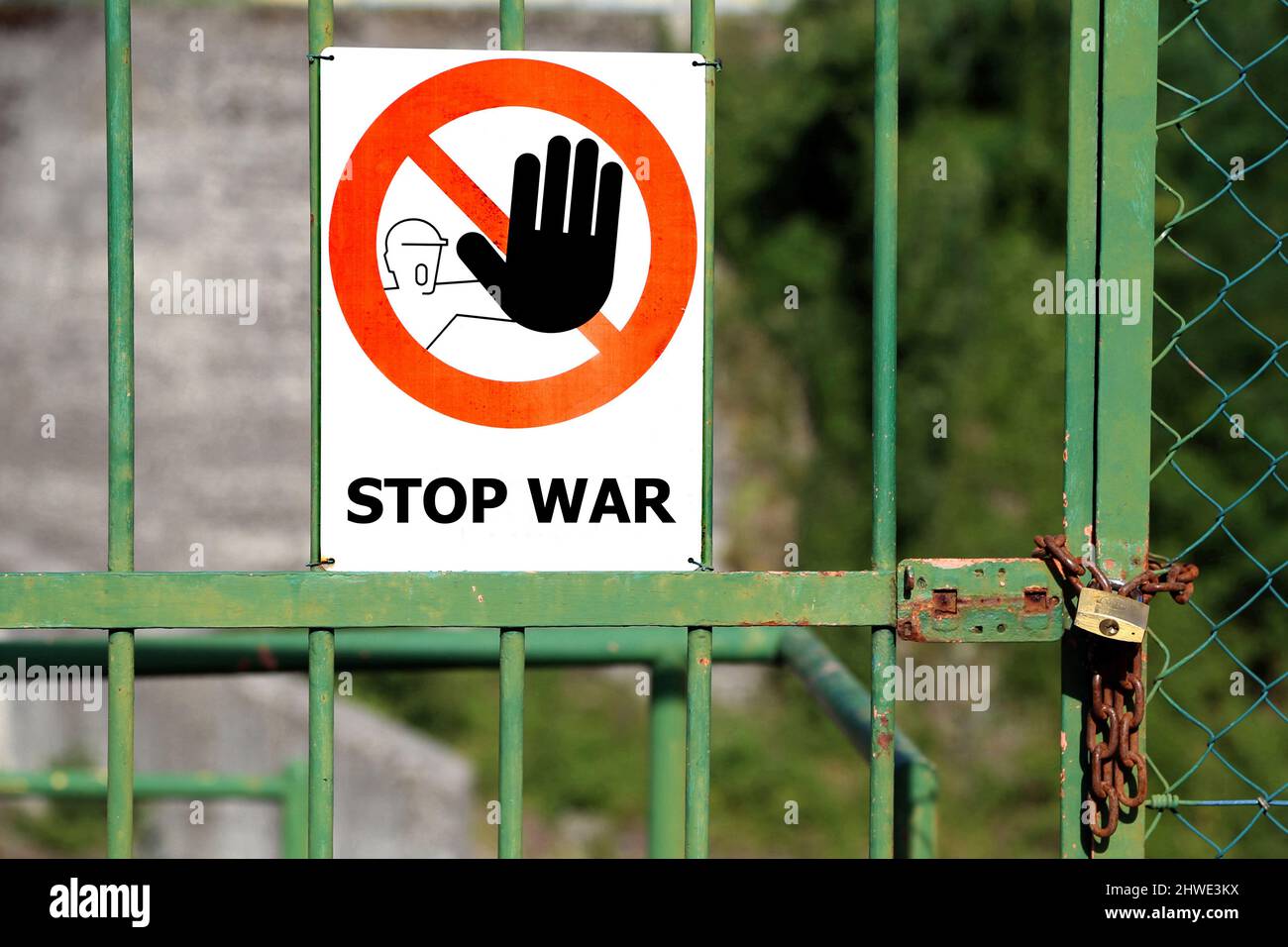 Panneau rouge avec une grande main noire indiquant d'arrêter et grand message Stop War en langue anglaise sur une porte fermée avec un cadenas Banque D'Images