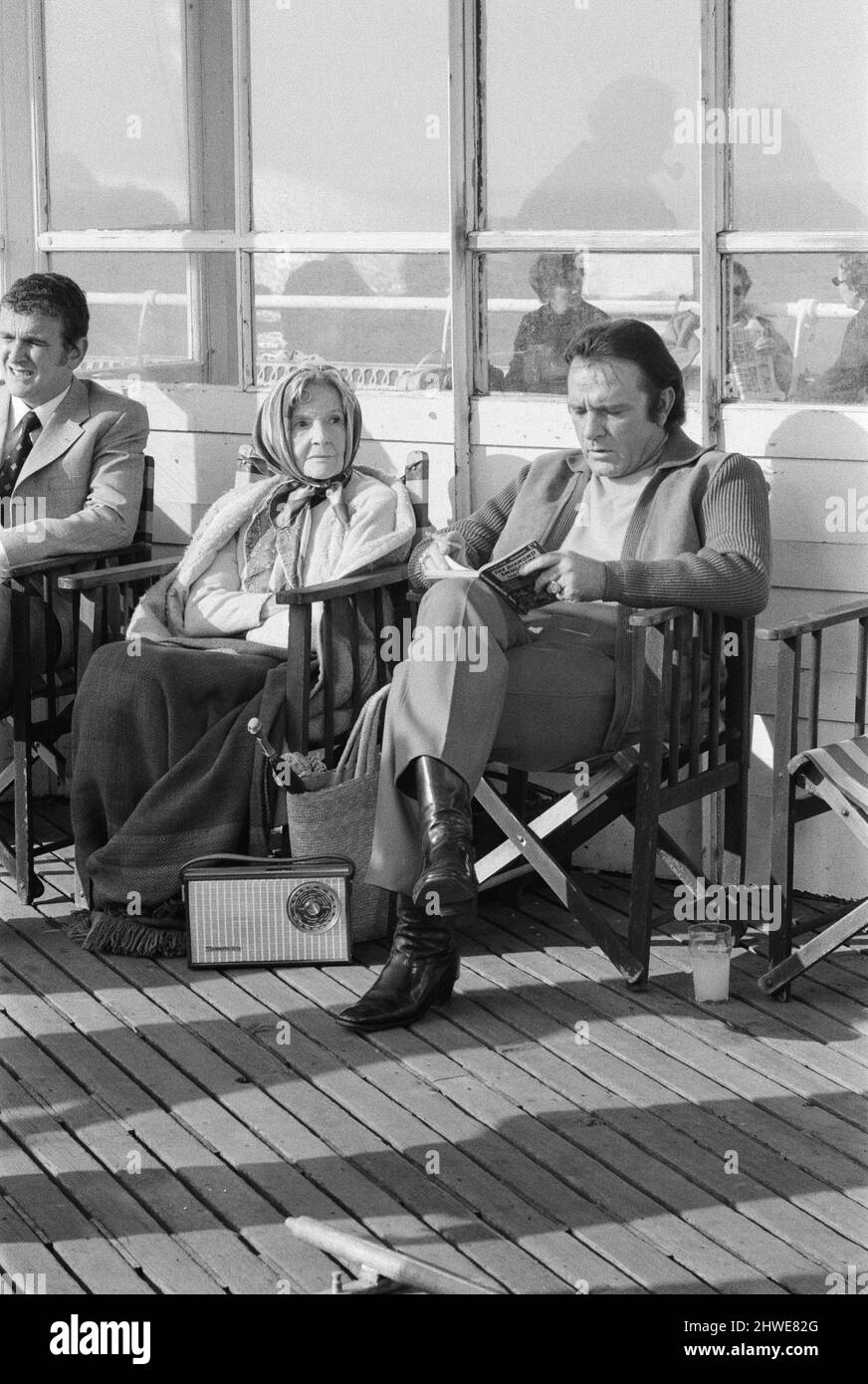 Richard Burton tournage Brighton, Sussex. Le film est appelé méchant. Richard Burton costars avec Ian McShane T. P. McKenna Donald Sinden Nigel Davenport Richard Burton a passé aujourd'hui assis sur Brighton Pier à lire un roman et à profiter du soleil, tout était dans une journée de tournage. Il prend la part d'un gangster londonien qui a pris sa vieille mère pour une journée à Brighton. Burton est en train de lire les contrebandiers Diamant de Ian Fleming, la vieille dame à sa droite est Cathleen Nesbitt qui joue sa mère. Photo prise le 16th octobre 1970 Banque D'Images