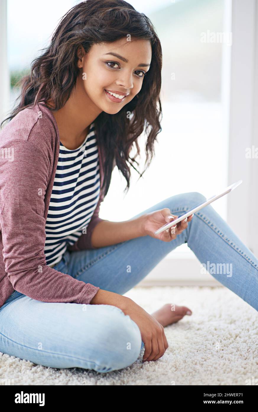 Voyons ce qui se passe en ligne. Prise de vue d'une jeune femme utilisant sa tablette numérique à la maison. Banque D'Images