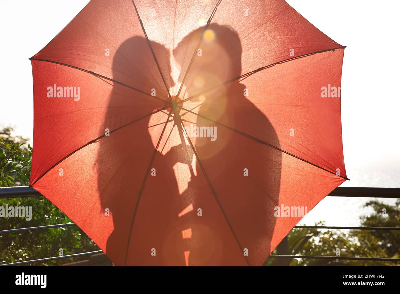 Amour caché. Silhouette d'un couple affectueux debout derrière un parapluie. Banque D'Images