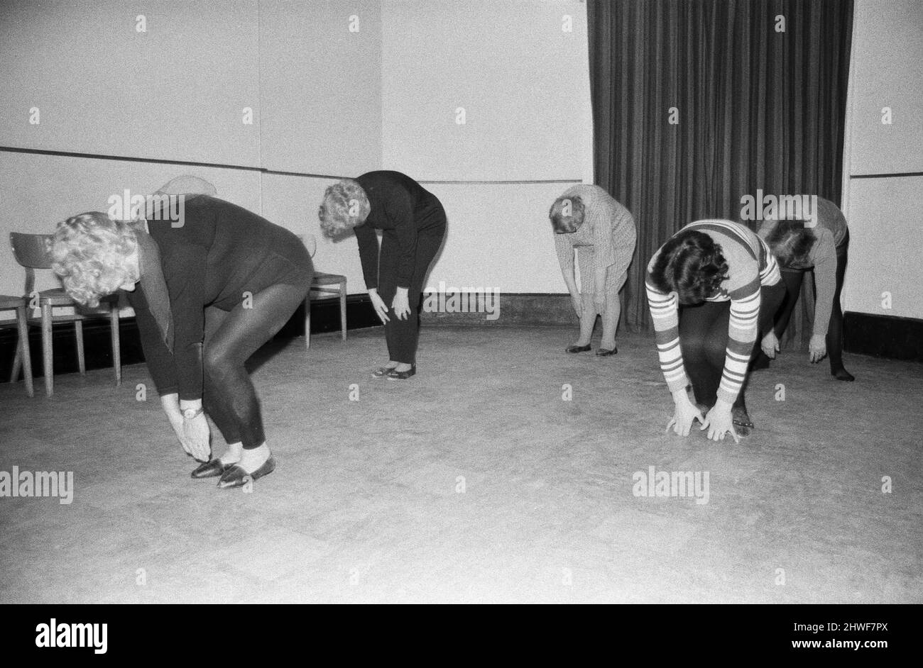 La grand-mère la plus étonnante de Cornwall, Mme Mary Wyatt (75 avril prochain), s'emboîte dans la nouvelle décennie de 1970s, vêtue de collants noirs de danse montrant une classe de femmes comment faire des étirements dynamiques et athlétiques de bras et de jambes à la musique. Mme Wyatt a tenu sa première classe Keep Fit du 1970s dans les salles communautaires du Guildhall de St Ives, en Cornouailles. 2nd janvier 1970.la grand-mère la plus étonnante de Cornwall, Mme Mary Wyatt (75 avril prochain) fait son entrée dans la nouvelle décennie de 1970s, vêtue de collants noirs de danse montrant une classe de femmes comment faire des bras et des jambes énergiques et athlétiques s'étire au mus Banque D'Images