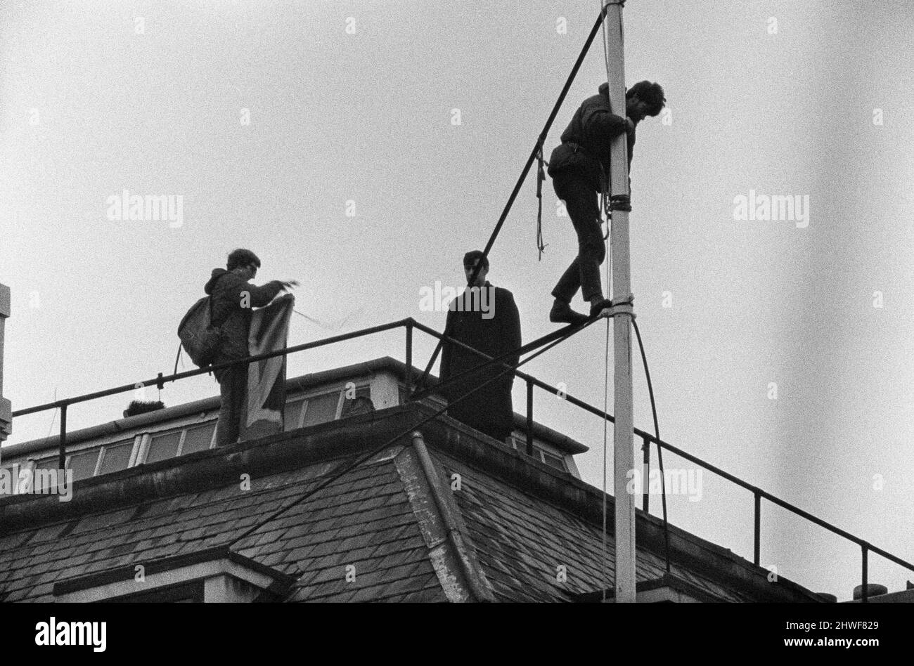 La scène sur le mât de la Rhodésie House en tant que policier regarde les deux hommes qui quittent le mât après la démonstration. L'un plie le cric Union tandis que l'autre retire l'équipement d'escalade du poteau. Ils ont mis à l'échelle le bâtiment avec leur drapeau la nuit précédente et ont soulevé l'Union Jack à la place du drapeau de Rhodésie. Au cours de la journée, il y a eu une marche anti Rhodésie. 12th janvier 1969. Banque D'Images La scène sur le mât de la Rhodésie House en tant que policier regarde les deux hommes qui quittent le mât après la démonstration. L'un plie le cric Union tandis que l'autre retire l'équipement d'escalade du poteau. Ils ont mis à l'échelle le bâtiment avec leur drapeau la nuit précédente et ont soulevé l'Union Jack à la place du drapeau de Rhodésie. Au cours de la journée, il y a eu une marche anti Rhodésie. 12th janvier 1969. Banque D'Images