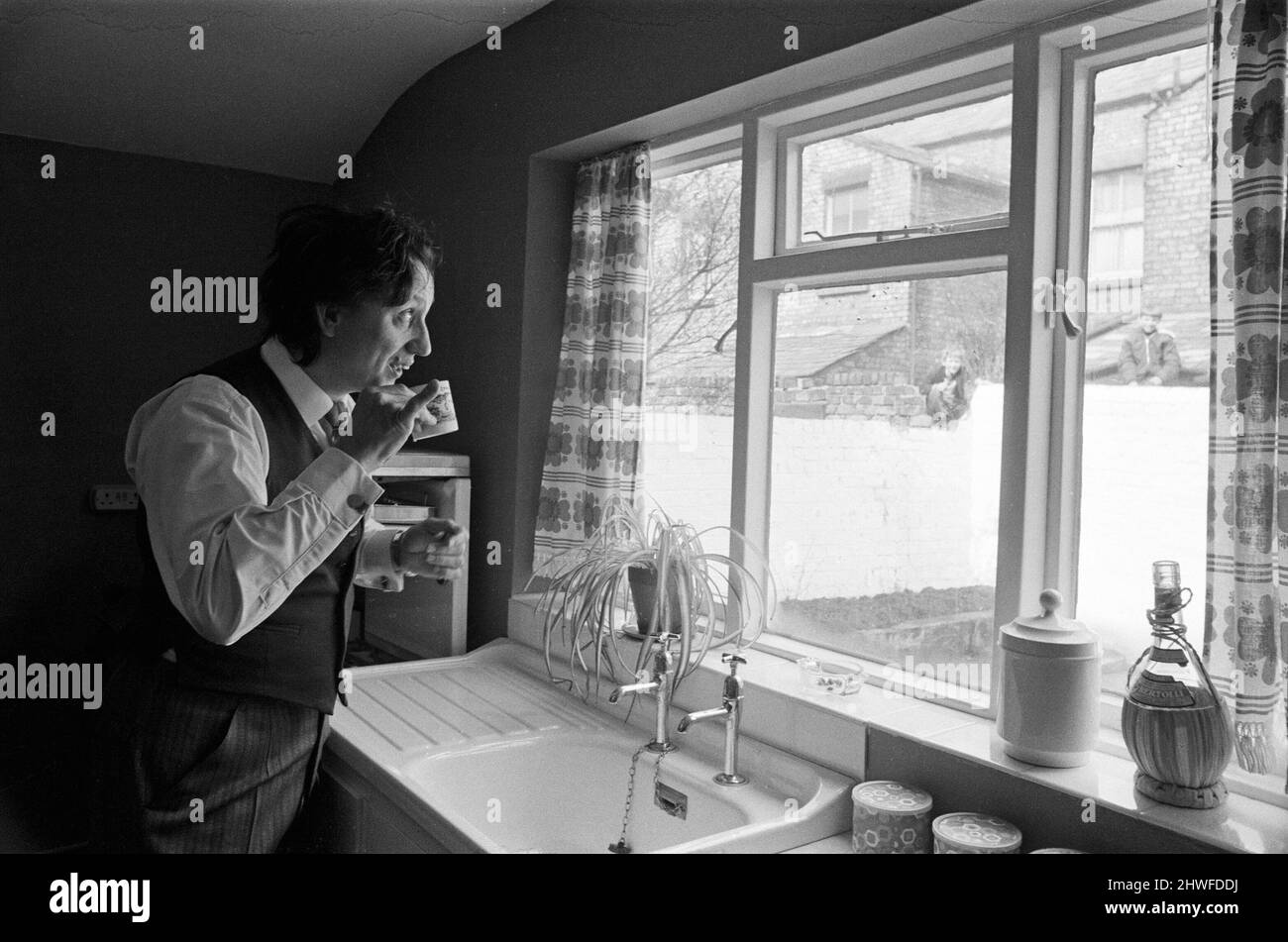 Le comédien Ken Dodd ouvre des appartements à Ducie Street et Beaconsfield Street, Toxteth, Liverpool. Deux maisons, une dans chaque rue, ont été converties en appartements sous la direction d'une équipe d'experts en logement et en planification. Ken boit une tasse d'eau dans la nouvelle cuisine de Mme Mrgaret Gibbs, rue Ducie. 7th avril 1970. Banque D'Images