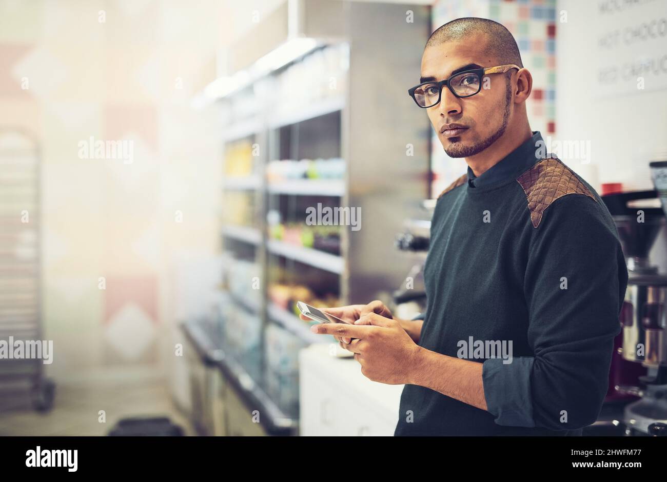Les médias sociaux jouent un rôle important dans la publicité. Photo d'un homme utilisant son téléphone portable tout en se tenant dans un café. Banque D'Images