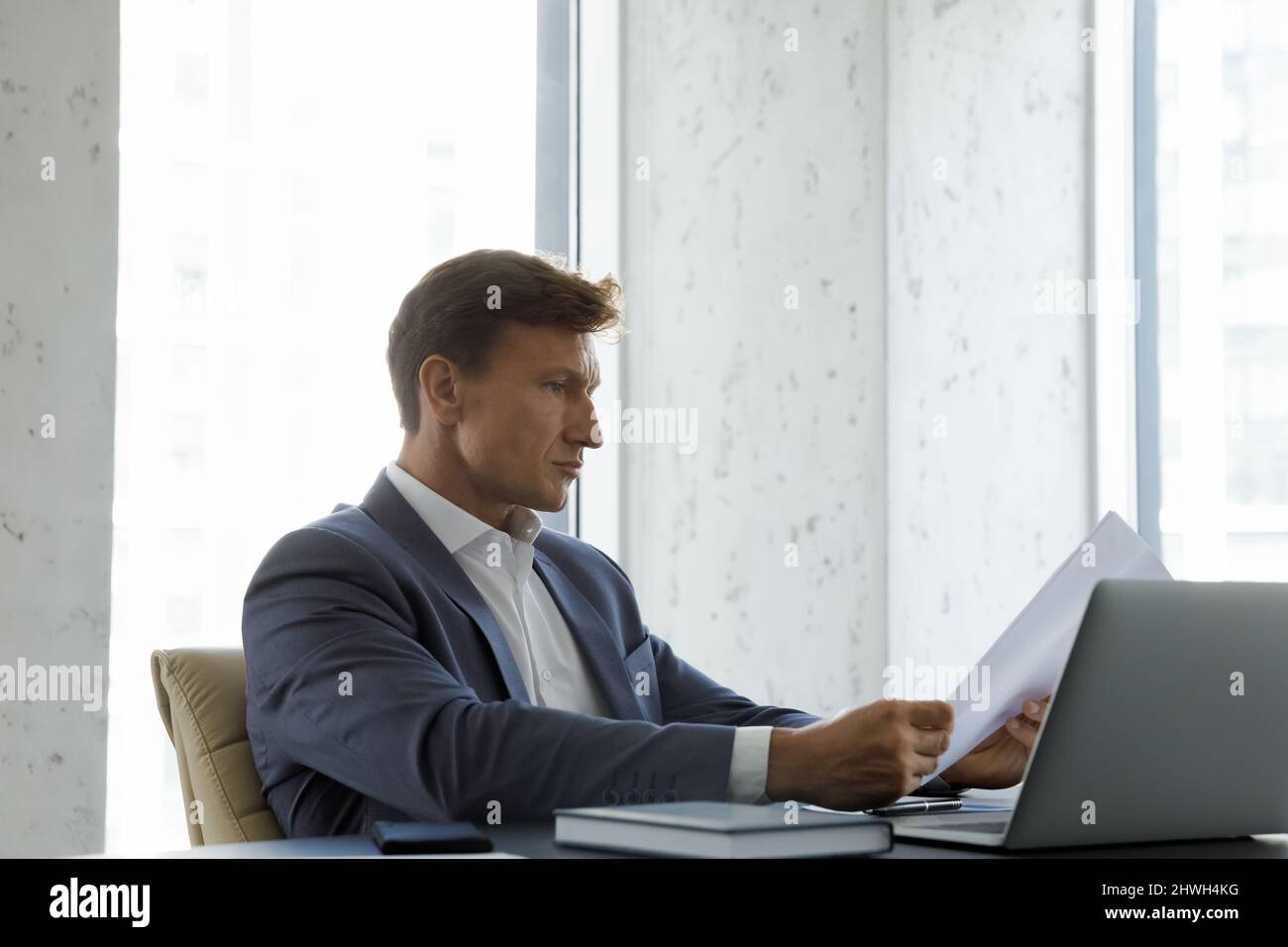 Un homme d'affaires spécialisé d'âge moyen de 40s ans qui lit un document. Banque D'Images
