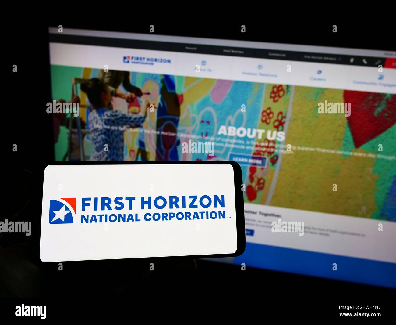 Personne tenant un téléphone mobile avec le logo de la société américaine First Horizon Corporation (FHN) à l'écran en face de la page Web. Mise au point sur l'affichage du téléphone. Banque D'Images