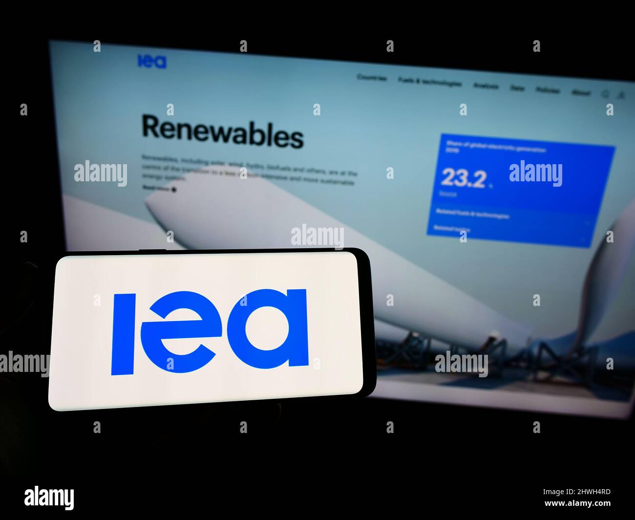 Personne tenant un smartphone avec le logo de l'organisation Agence internationale de l'énergie (AIE) sur l'écran devant le site Web. Mise au point sur l'affichage du téléphone. Banque D'Images