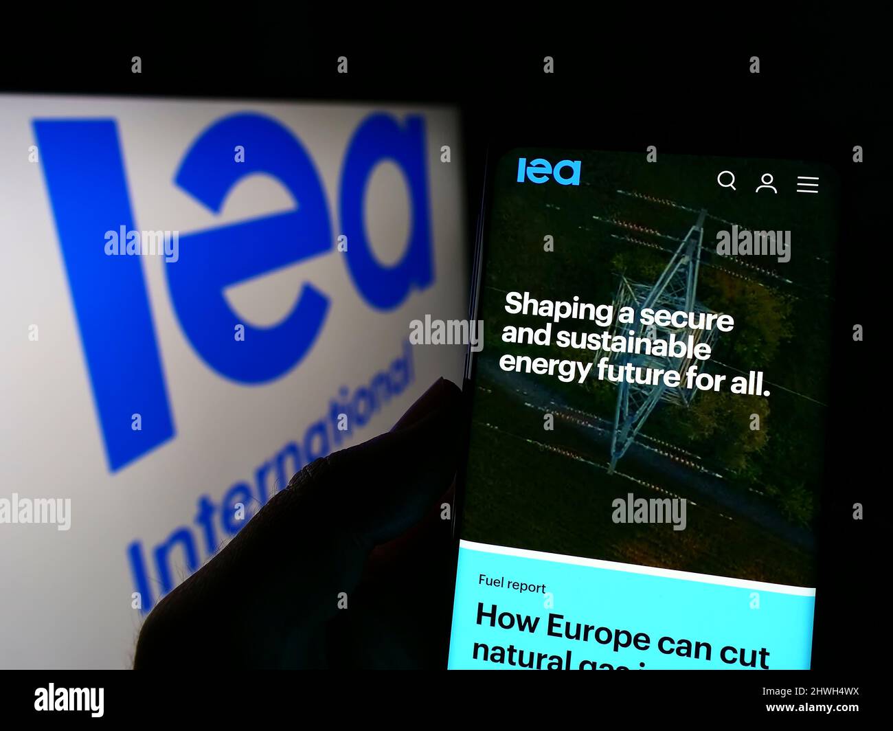 Personne tenant un téléphone portable avec le site Internet de l'organisation Agence internationale de l'énergie (AIE) à l'écran avec logo. Concentrez-vous sur le centre de l'écran du téléphone. Banque D'Images