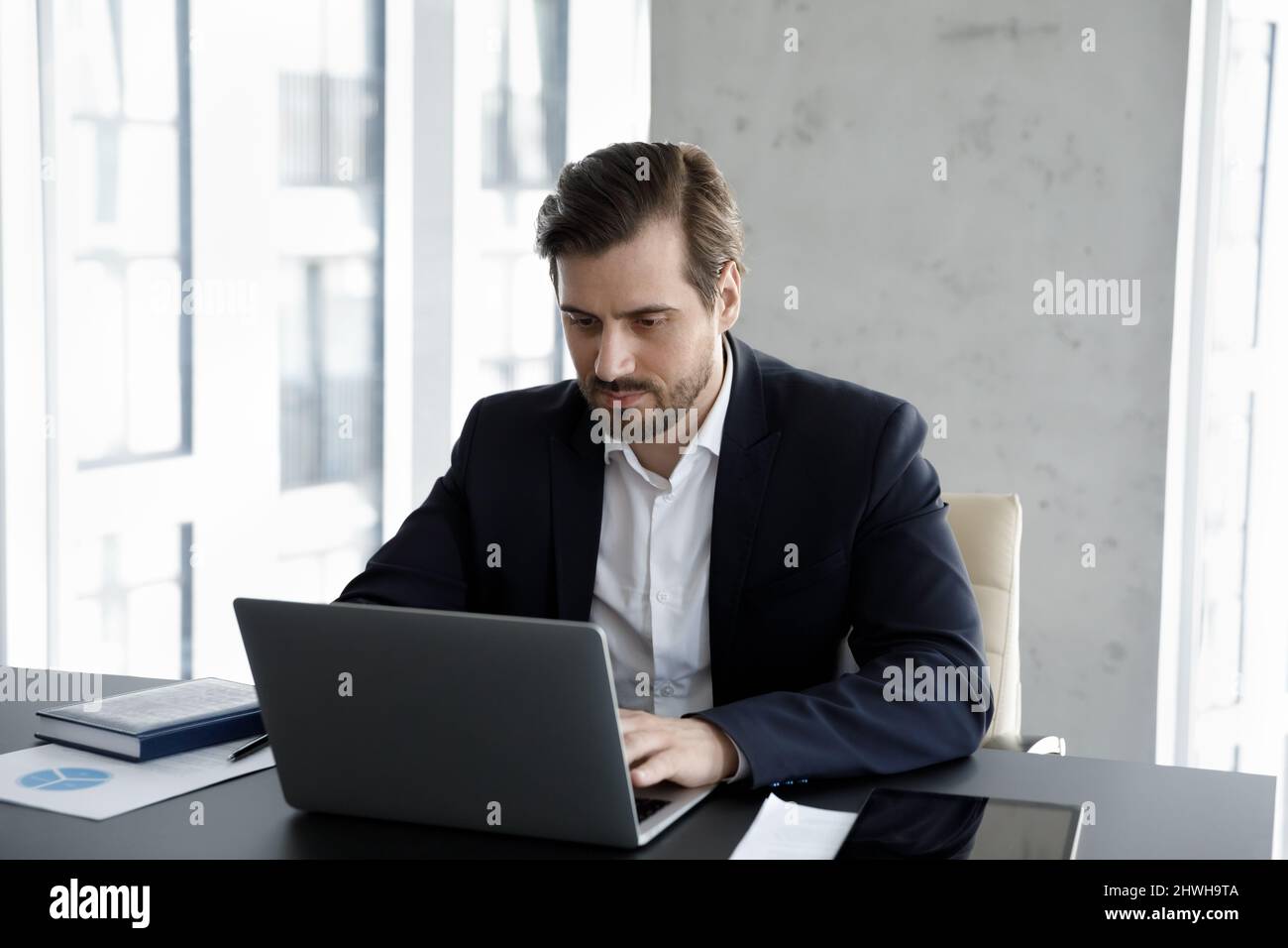 Jeune homme attentif et concentré responsable travaillant sur l'ordinateur. Banque D'Images