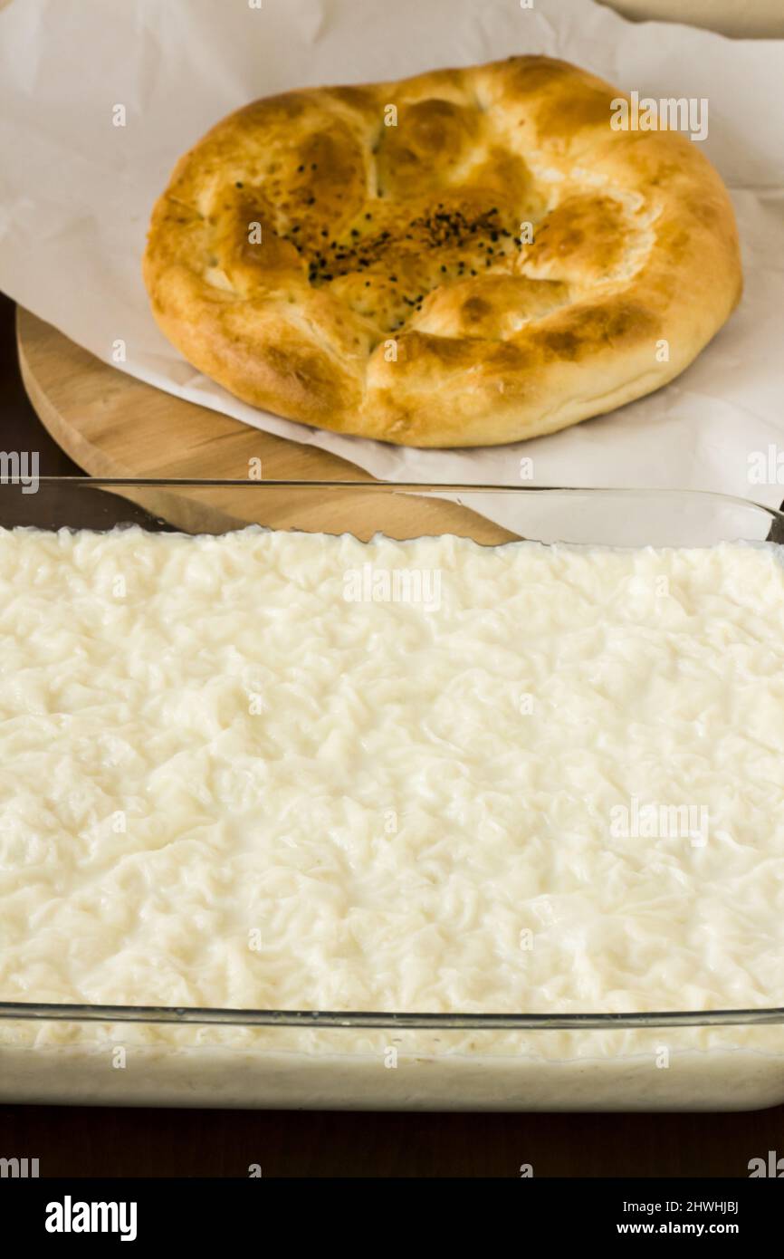 Traditionnel turc Ramadan Milky dessert, Gullac dans un récipient en verre sur une table en bois avec du pain circulaire frais de Ramadan Banque D'Images