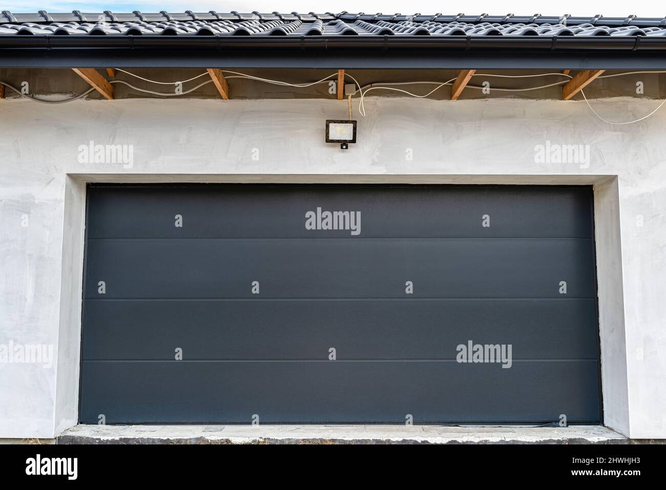 Porte de garage anthracite fermée avec une lampe visible pour le détecteur de mouvement, vue de l'extérieur. Banque D'Images