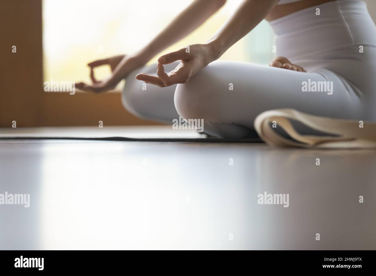 Image rognée femme ne pratique de méditation assis à pieds croisés sur le tapis Banque D'Images
