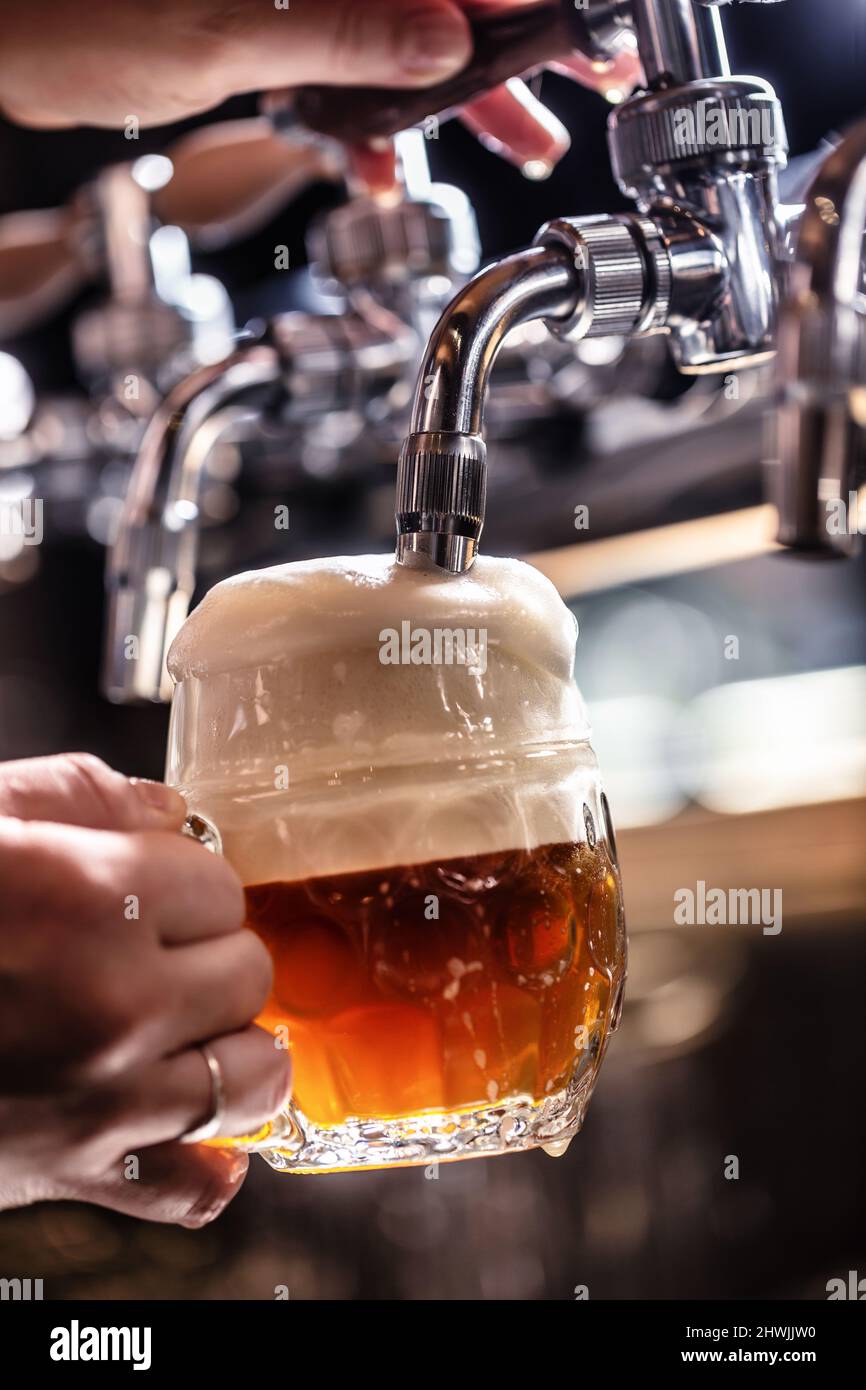 Mélanger la bière foncée avec la lumière dans une tasse en la tapotant d'un robinet pour créer une mousse riche. Banque D'Images