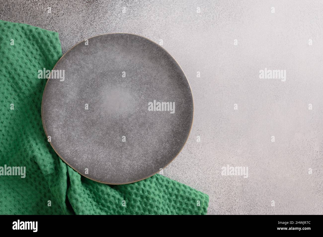 Assiette grise et serviette verte sur table grise pour votre menu ou votre recette. Dîner de la Saint-Patrick. Vue de dessus. Copier l'espace. Banque D'Images