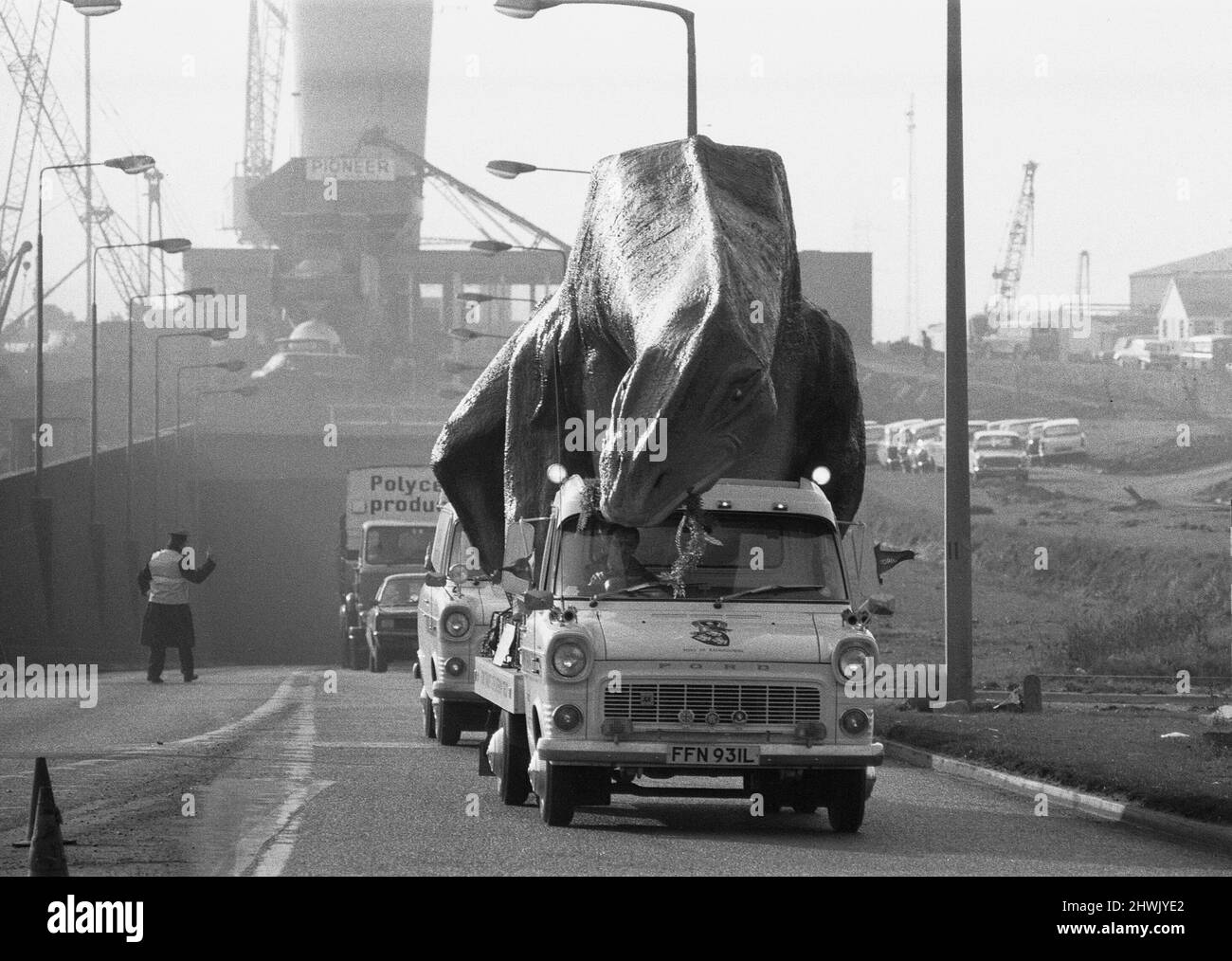 Un dinosaure en mouvement dans l'Essex. Un Cetiosaurus de 16 pieds de haut et de 45 pieds de long, une espèce de dinosaure, fabriqué par M. Alan Ross, a quitté Ramsgate ce matin en route pour Aviemore, en Écosse, via le tunnel de Dartford. Le modèle restera pendant deux ou trois semaines sur Canvey, tandis que d'autres monstres préhistoriques fabriqués par M. Ross le rejoignent avant de se rendre en Écosse, où M. Ross ouvre un parc préhistorique. Le Cetiosaurus vu ici émergeant du tunnel de Dartford dans l'Essex après avoir été escorté à travers le tunnel par le contrôle de la circulation . 31st janvier 1973 Banque D'Images