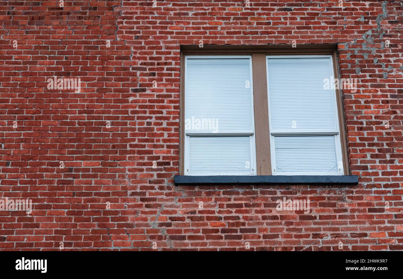 Fenêtre dans le mur de briques. Fenêtre avec stores fermés dans une maison urbaine en briques rouges en clinker. Photo de rue, personne, mise au point sélective, espace de copie pour le texte Banque D'Images