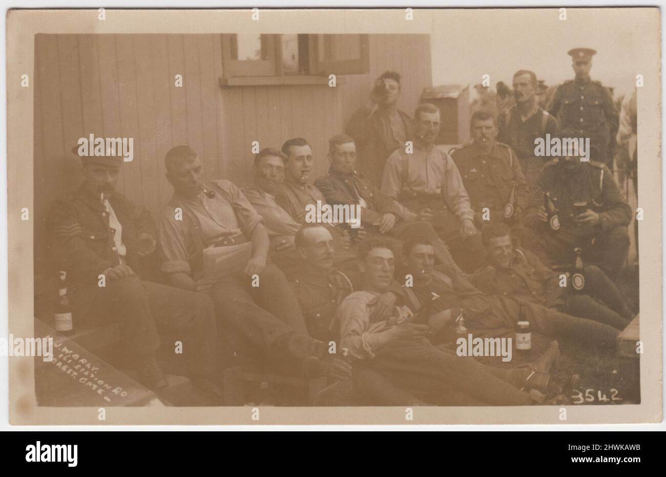 Photographie informelle des soldats qui boivent de la bière dans un camp militaire de la première Guerre mondiale dans la région de Forest Gate, Londres. Le groupe est assis et allongé à l'extérieur de l'une des cabanes avec des bouteilles de bière, des verres et des pipes de tabac. Un soldat lit son journal. La photo a été prise par H.J.W. Bray, 161 Station Road, Forest Gate Banque D'Images