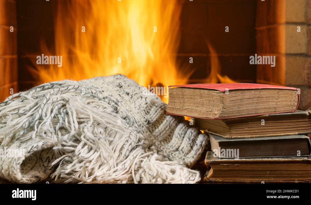 Écharpe en laine chaude et vieux livres sur un fond de foyer. Banque D'Images
