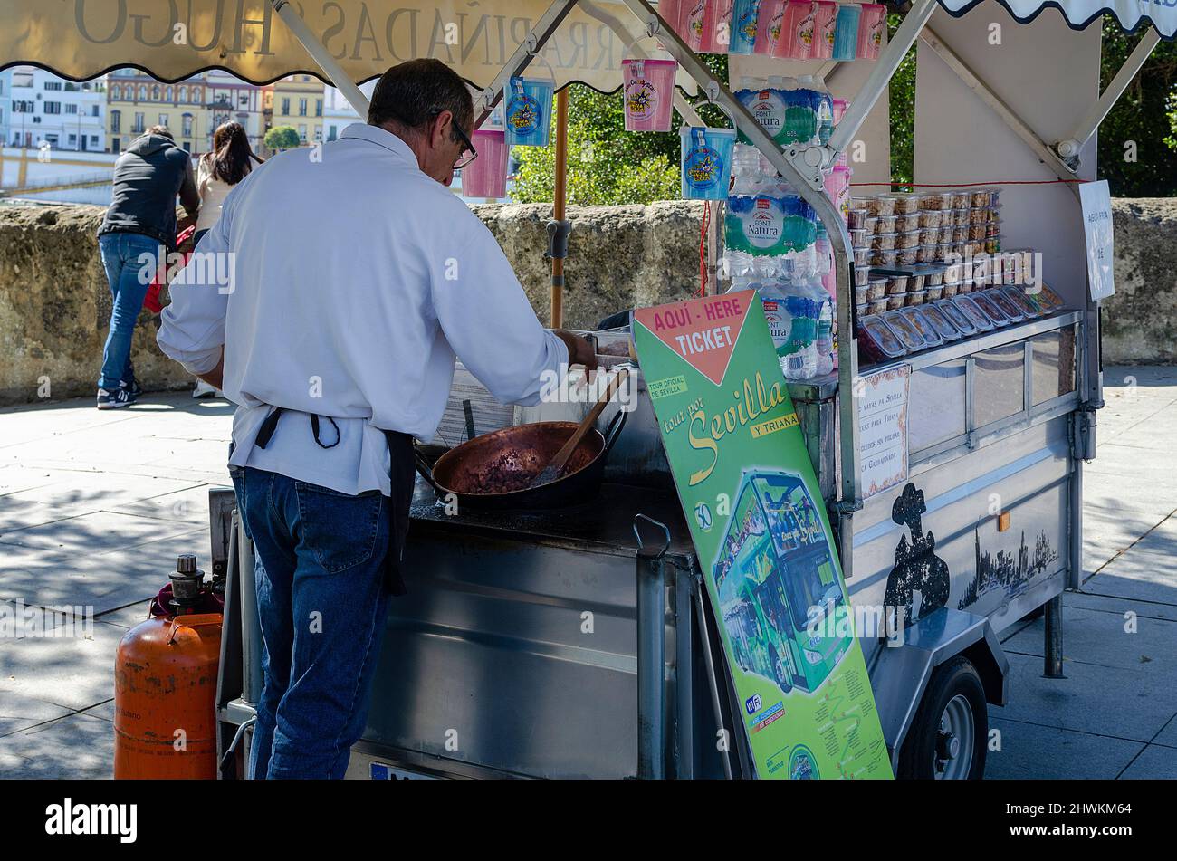 Vue arrière d'un homme préparant des amandes grillées au miel. Stand de cuisine de rue Banque D'Images