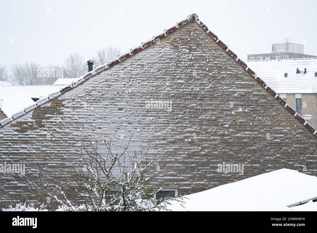 Un mur d'une maison est couvert de neige pendant un blizzard. Effet texturé sur le mur d'une maison, causé par le souffle de neige pendant une tempête de neige. Banque D'Images