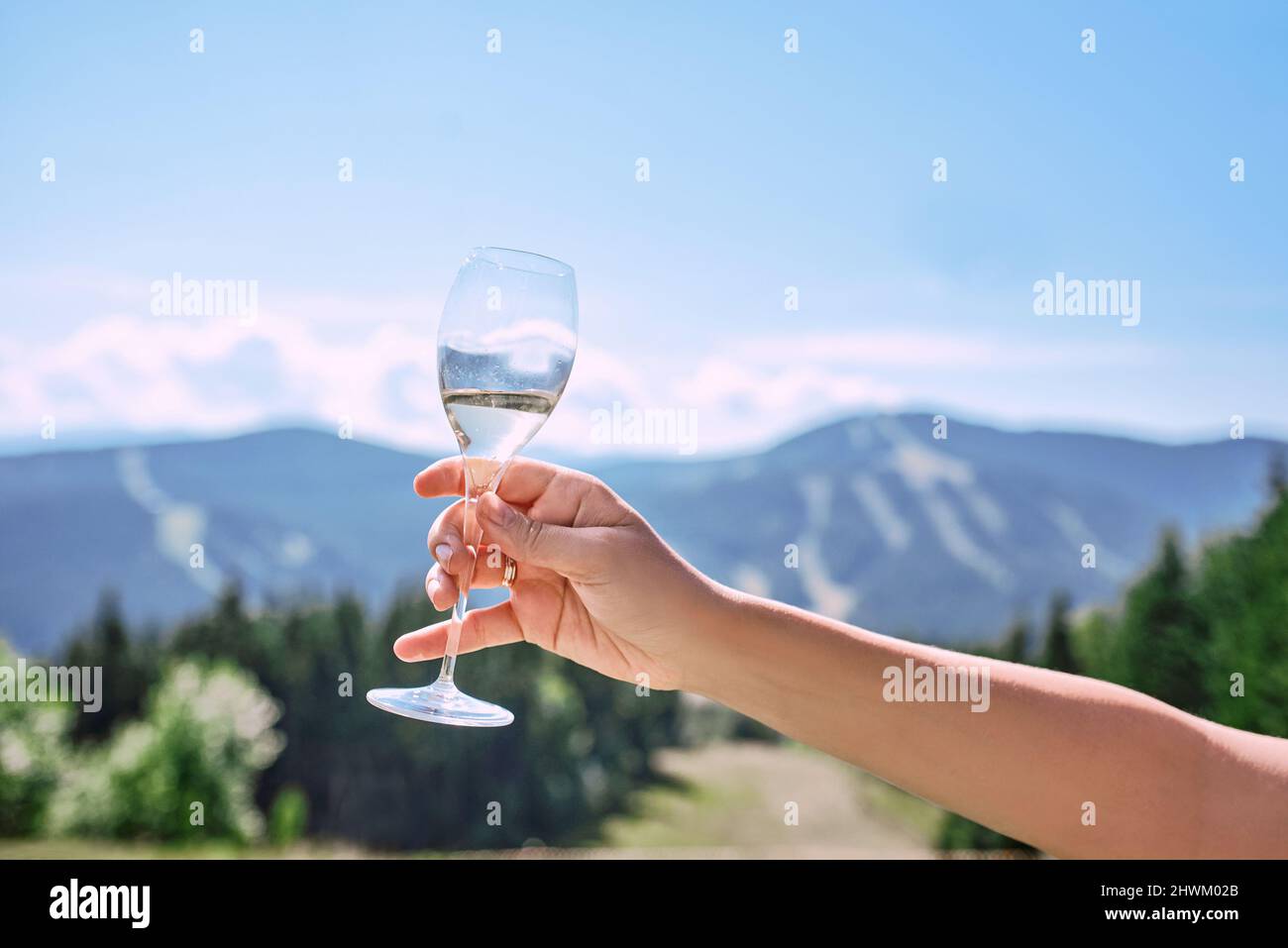 main avec un verre de vin mousseux sur fond de montagnes Banque D'Images