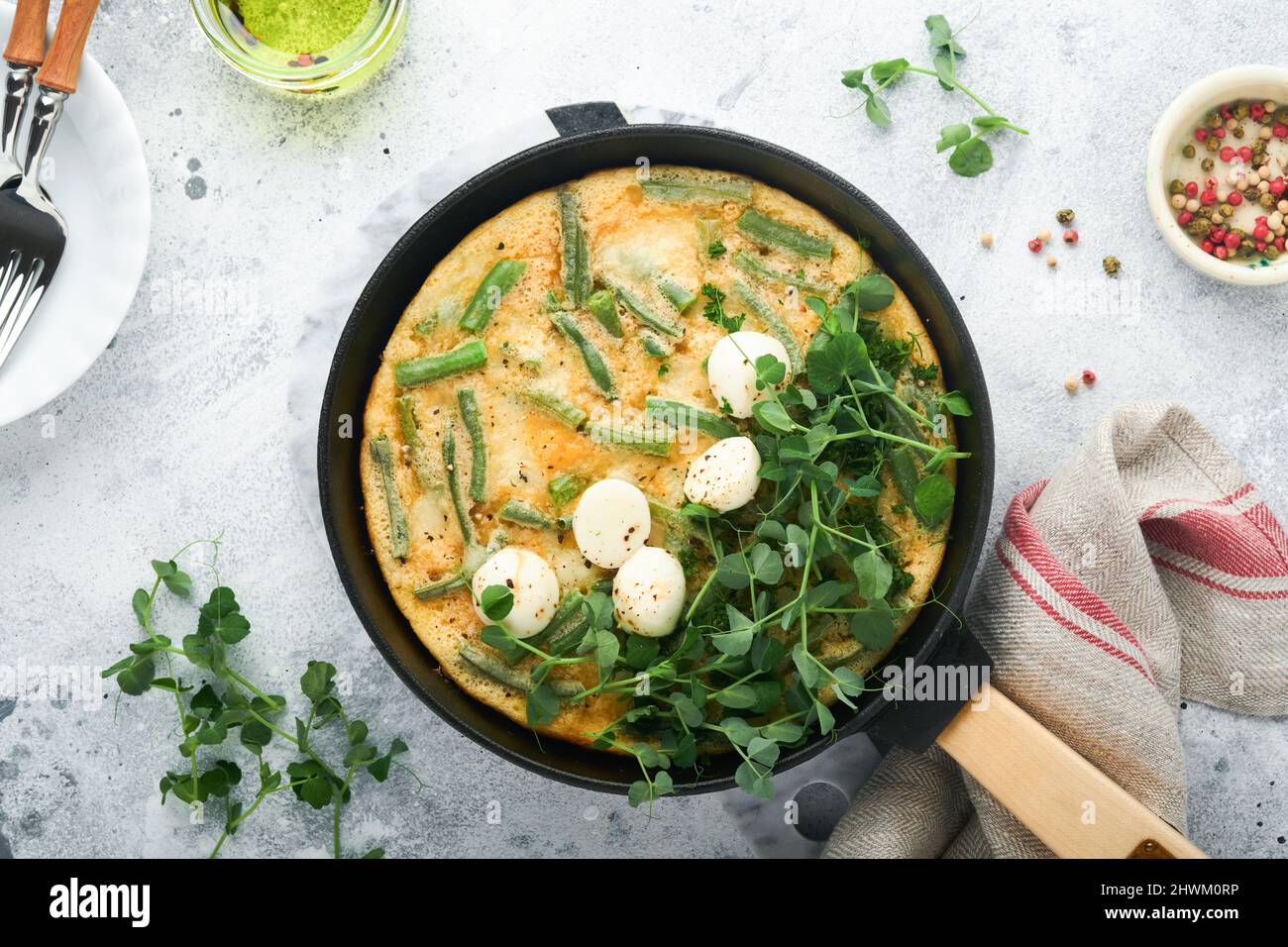 Omelette aux épinards, haricots verts, pommes de terre et épinards aliments sains dans une poêle noire sur fond rustique vieux de pierre grise. Frittata traditionnelle pour br Banque D'Images