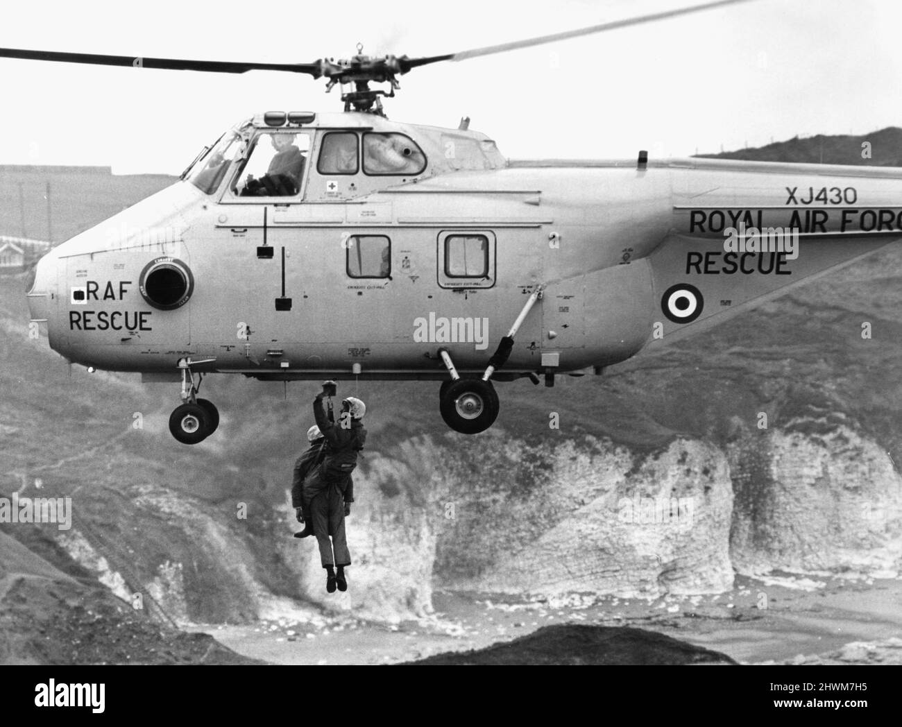 Winchman Norman Harris et le garde-côtes Bob Newsome étant soulevés dans un hélicoptère à tourbillon HAR10 de la RAF Westland alors qu'il survole les falaises de Flamborough. L'avion et l'équipage prenaient part à un exercice surveillé par le vice-maréchal de l'air C V Winn, AOC 18 Maritime Group. 1st mars 1973 Banque D'Images