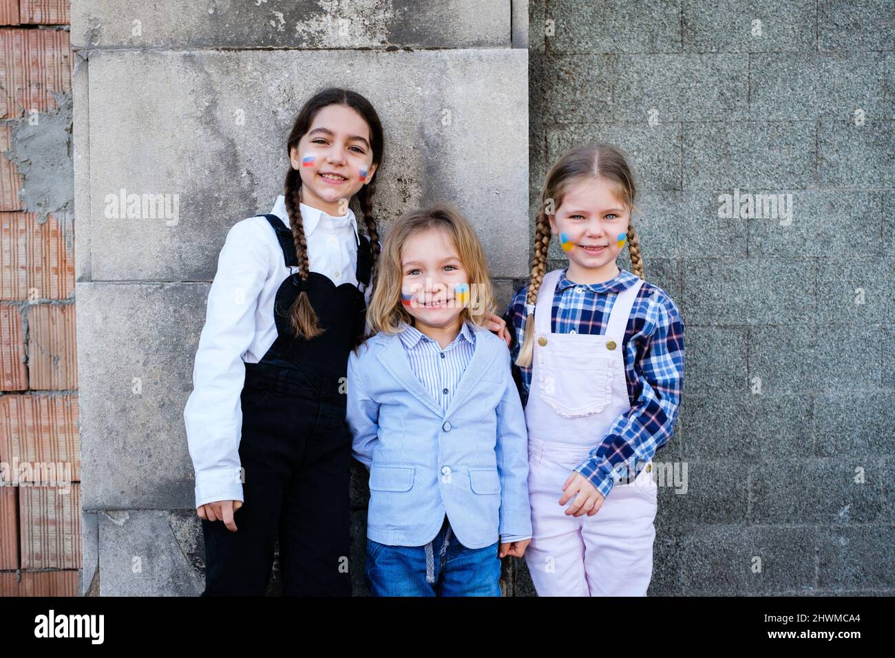 Portrait de trois enfants du caucase qui embrassent les visages avec des drapeaux russes et ukrainiens. Concept de paix, arrêter la guerre et l'amitié Banque D'Images