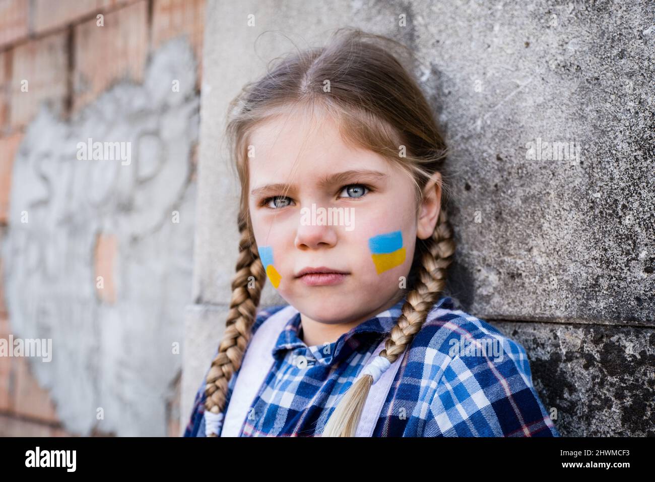 Portrait d'une fille effroyée avec drapeau peint sur la joue dans les couleurs jaune-bleu du drapeau ukrainien. Concept de paix et de protection des enfants Banque D'Images