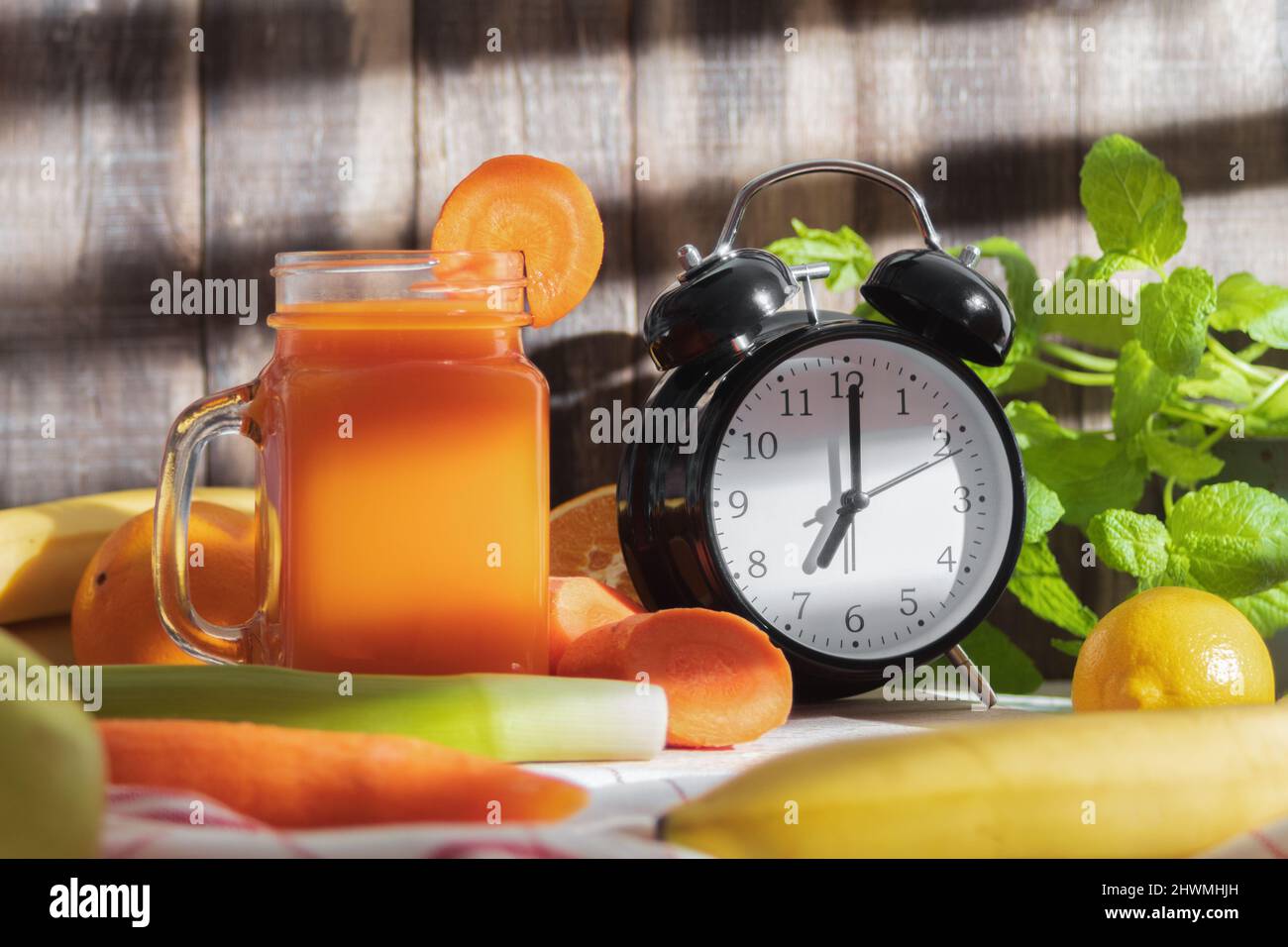 Le réveil indique 7,00. Et du jus de légumes frais dans un verre. Un verre de délicieux jus de fruits fraîchement pressé. Arrière-plan avec espace de copie Banque D'Images