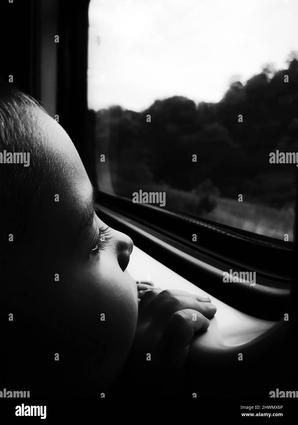 Triste petit garçon regardant par la fenêtre dans le train en gros plan Banque D'Images