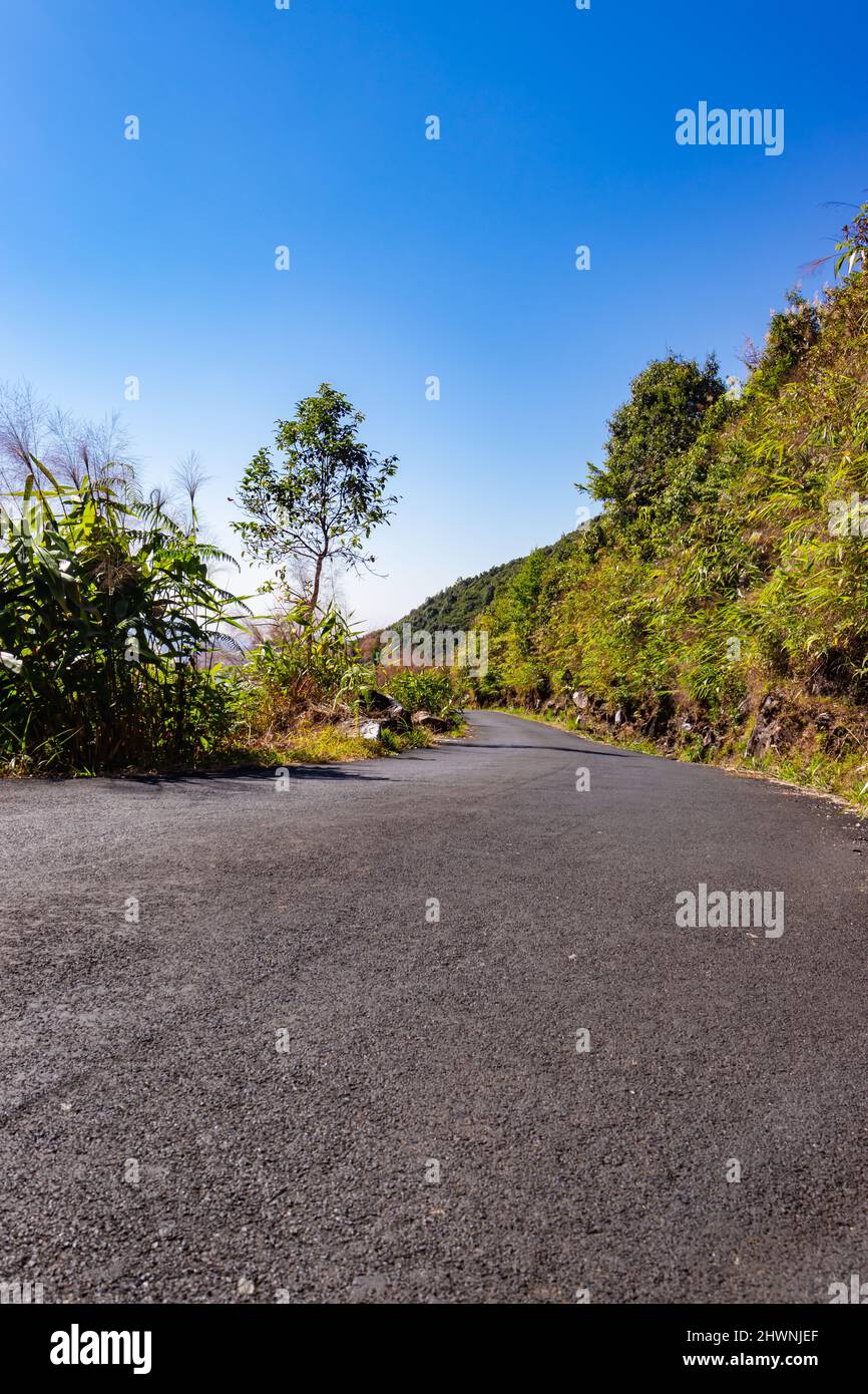 route tamac de montagne isolée avec des forêts et ciel bleu vif au matin image est prise à meghalaya inde. Banque D'Images