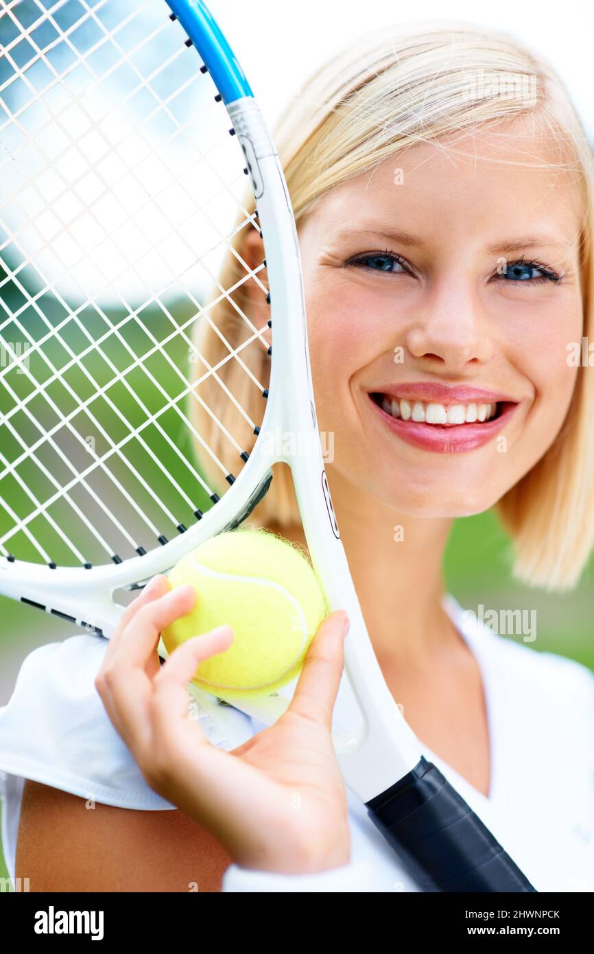 Apporter la beauté au jeu. Portrait d'une jeune joueuse de tennis tenant une balle et une raquette. Banque D'Images