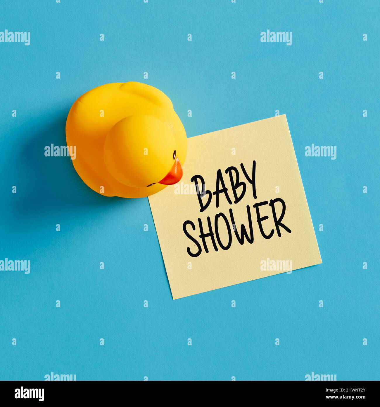 Message de rappel de fête de douche de bébé écrit sur une note autocollante jaune avec un canard en caoutchouc sur fond bleu. Banque D'Images