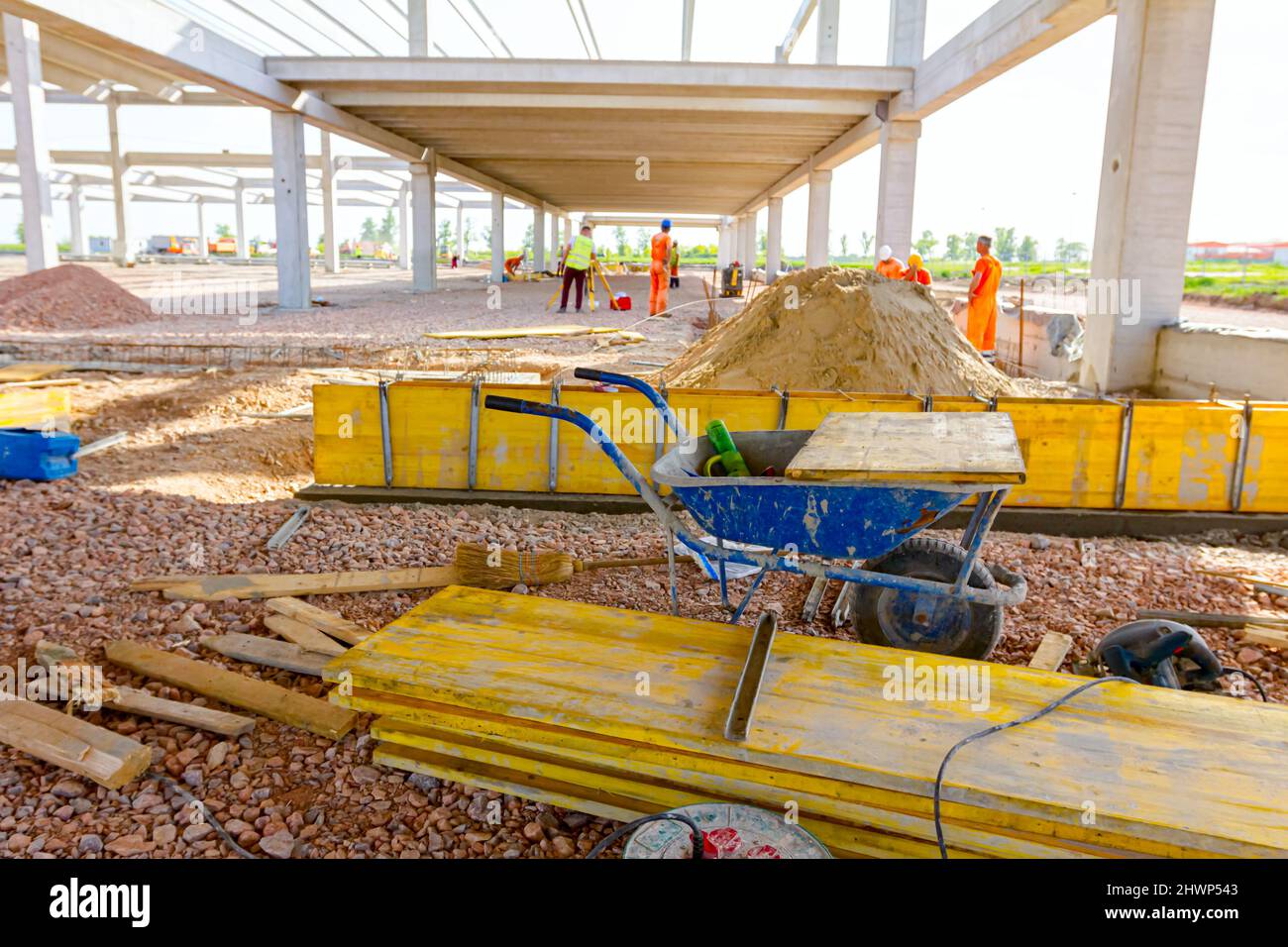 Vue sur les brouettes d'occasion avec des planches en bois peintes et empilées sont empilées sur le chantier. Les fauteurs, les travailleurs sont des moules longs d'assemblage pour le béton. Banque D'Images