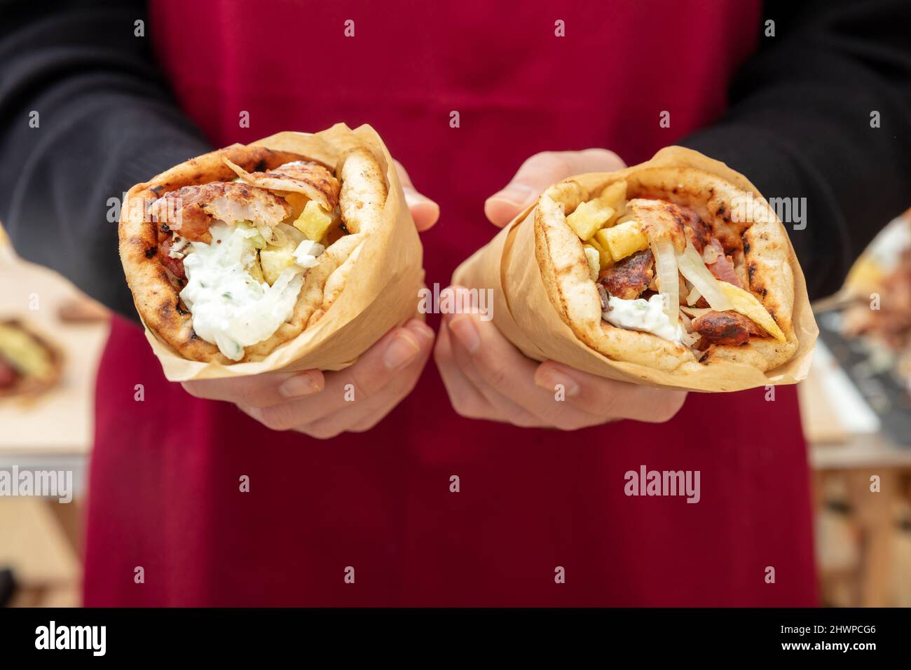 Gyro pita Shawarma. Cuisine grecque, viande en tranches, pomme de terre, tomate et tzatziki, papier d'emballage à main masculine, vue rapprochée. Banque D'Images