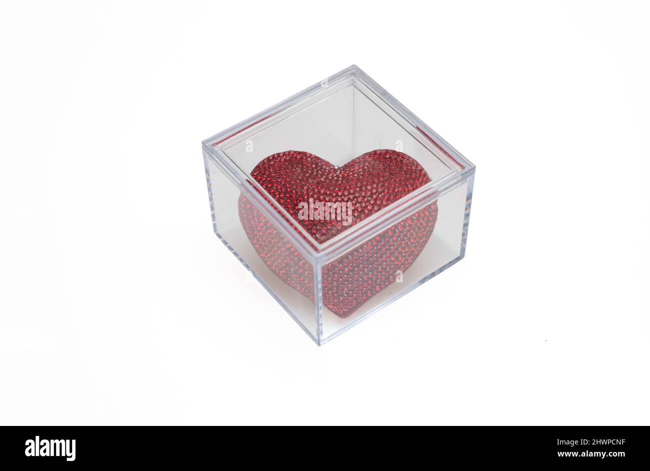 Cube de verre de couleur rouge rubis coeur en forme de bijou découpe isolée sur fond blanc. Vue de dessus de la boîte carrée transparente avec symbole d'amour, ann Banque D'Images