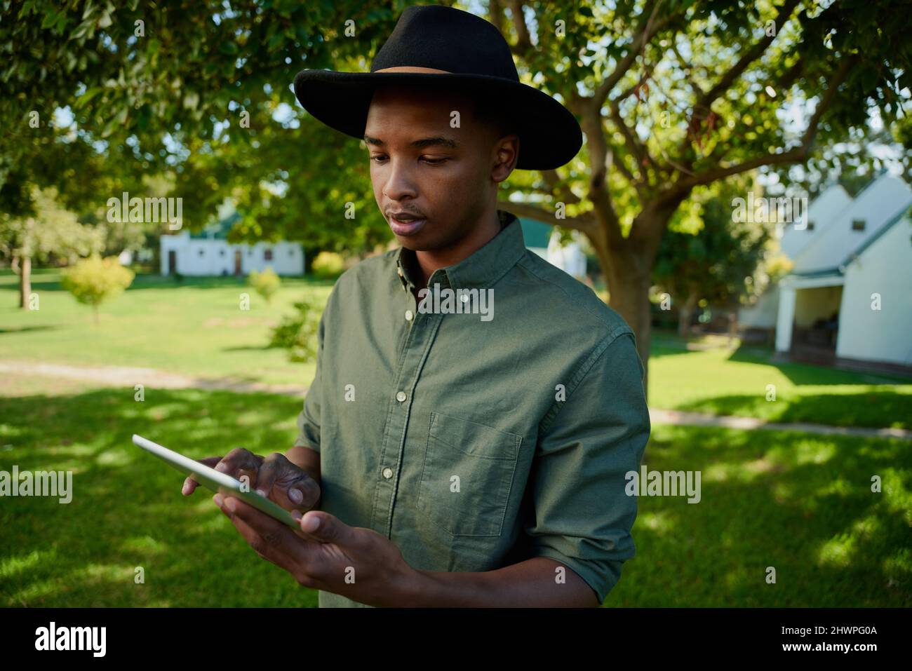 Fermier de race mixte debout à l'extérieur dactylographiant sur une tablette numérique Banque D'Images