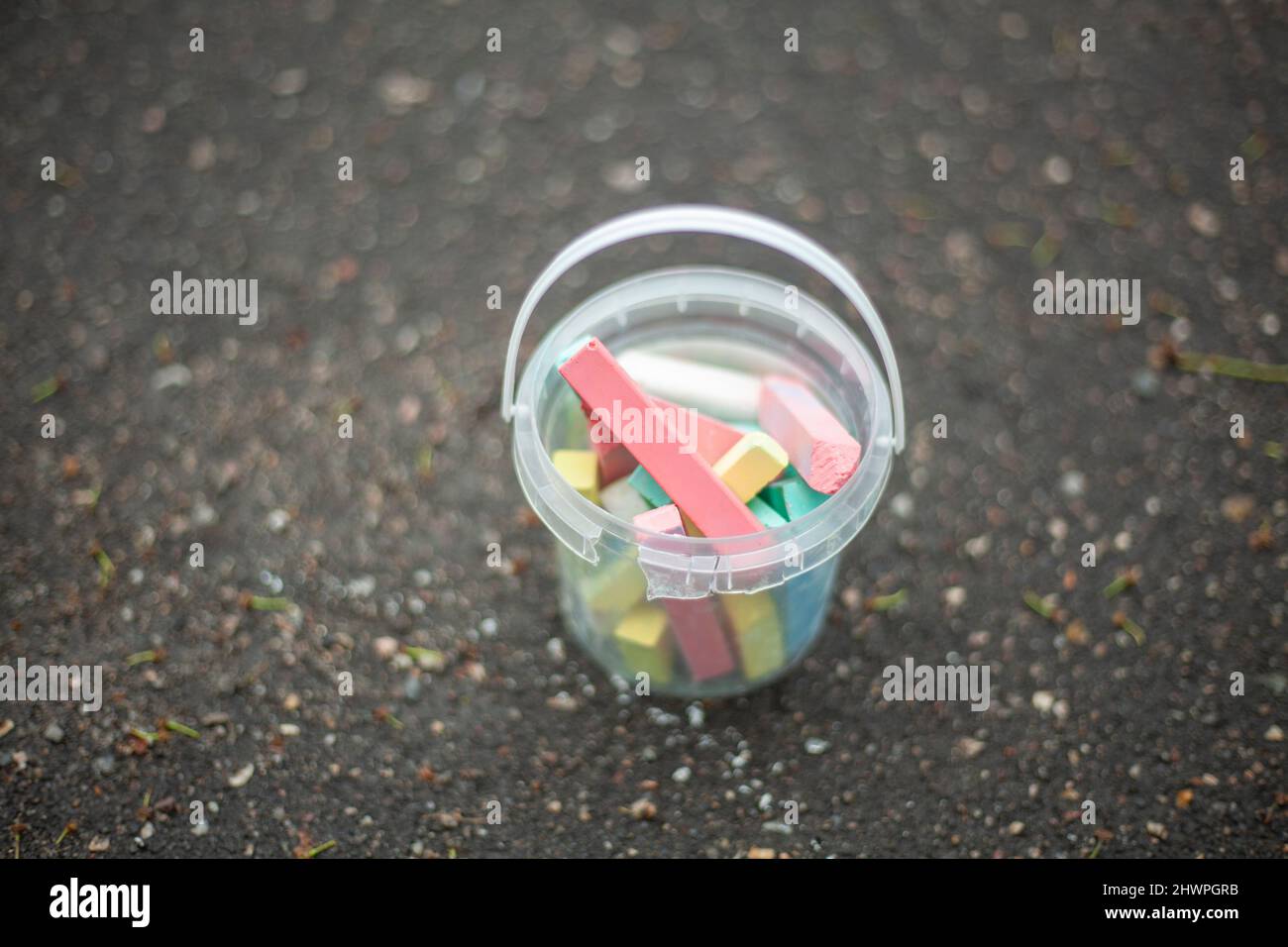 Crayons pour dessiner sur l'asphalte. Craie dans le seau. Jouons dehors pour les enfants. Détails de la créativité des enfants. Crayons multicolores en plas transparent Banque D'Images