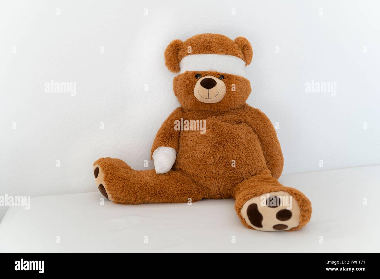 Ours en peluche brun avec bandage sur le lit Banque D'Images