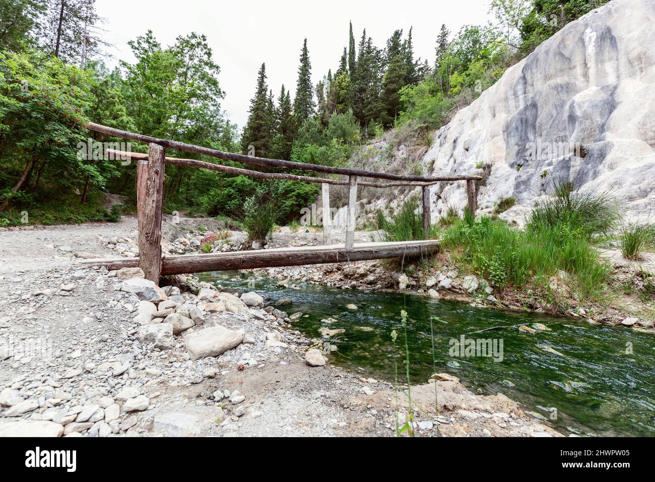 Petit pont en bois au-dessus du ruisseau d'eau minérale dans la source thermale toscane Bagni San Filippo. Val d'Orcia, Italie Banque D'Images