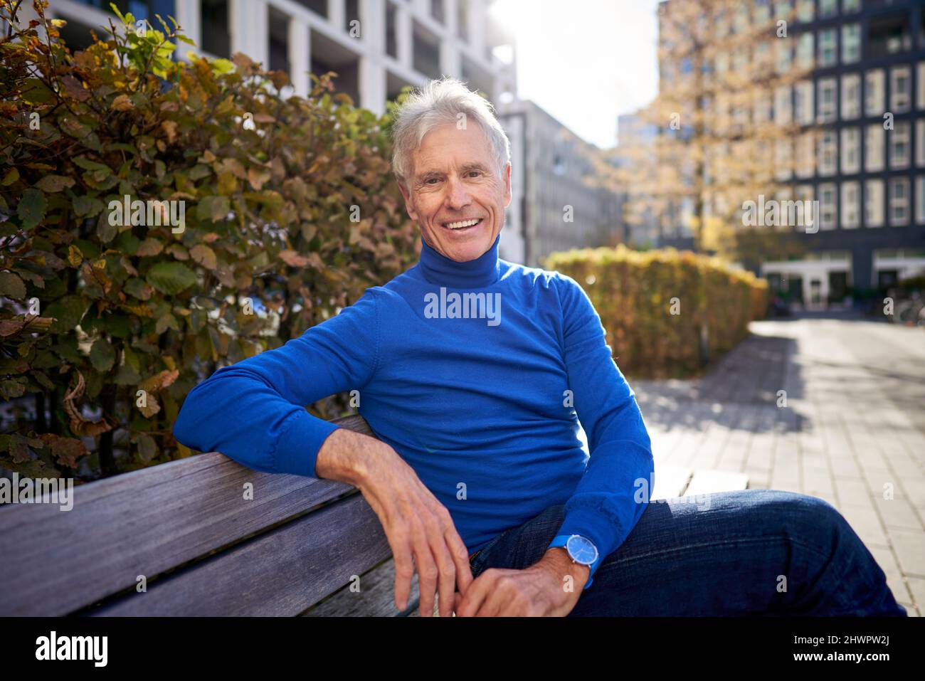 Joyeux homme senior assis sur le banc Banque D'Images